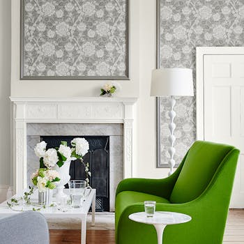 Sophisticated living space with a bold green chair and walls featuring framed panels of floral wallpaper in Gustav - Trophy